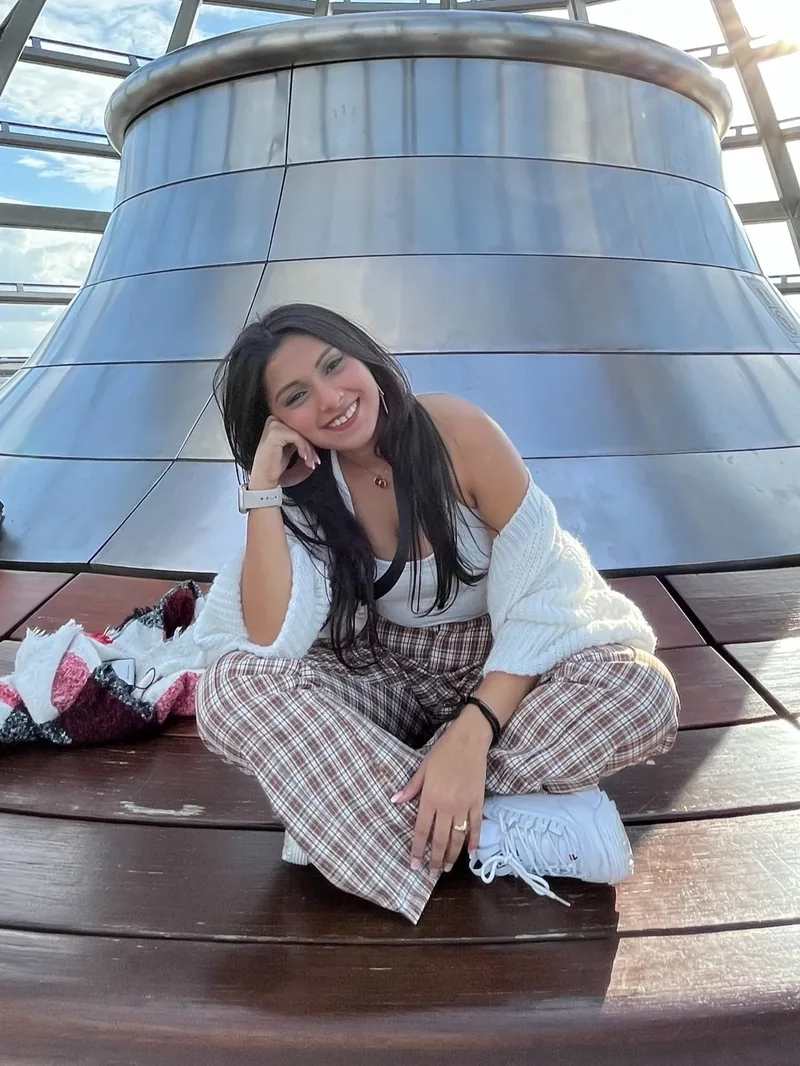 Shilpi Chakravorty sitting cross-legged on a wooden deck under a glass dome, laughing.